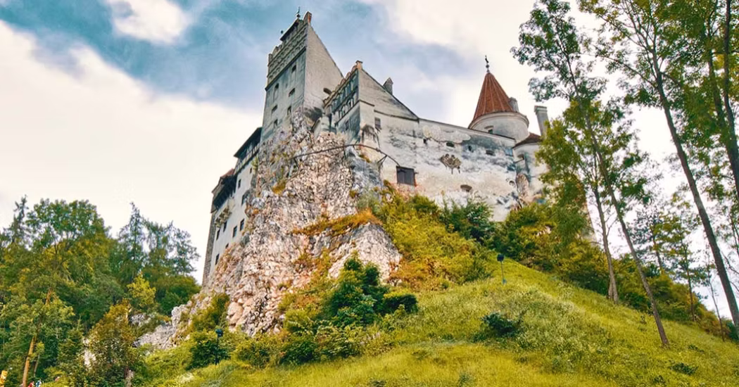 Bran Castle view from the side with trees surrounding it.
